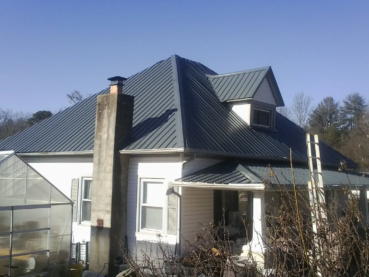 Dark blue standing seam metal roof on a white farmhouse with dormer — Slate & Tile Roof Repair by Roofing Brothers in Cammal