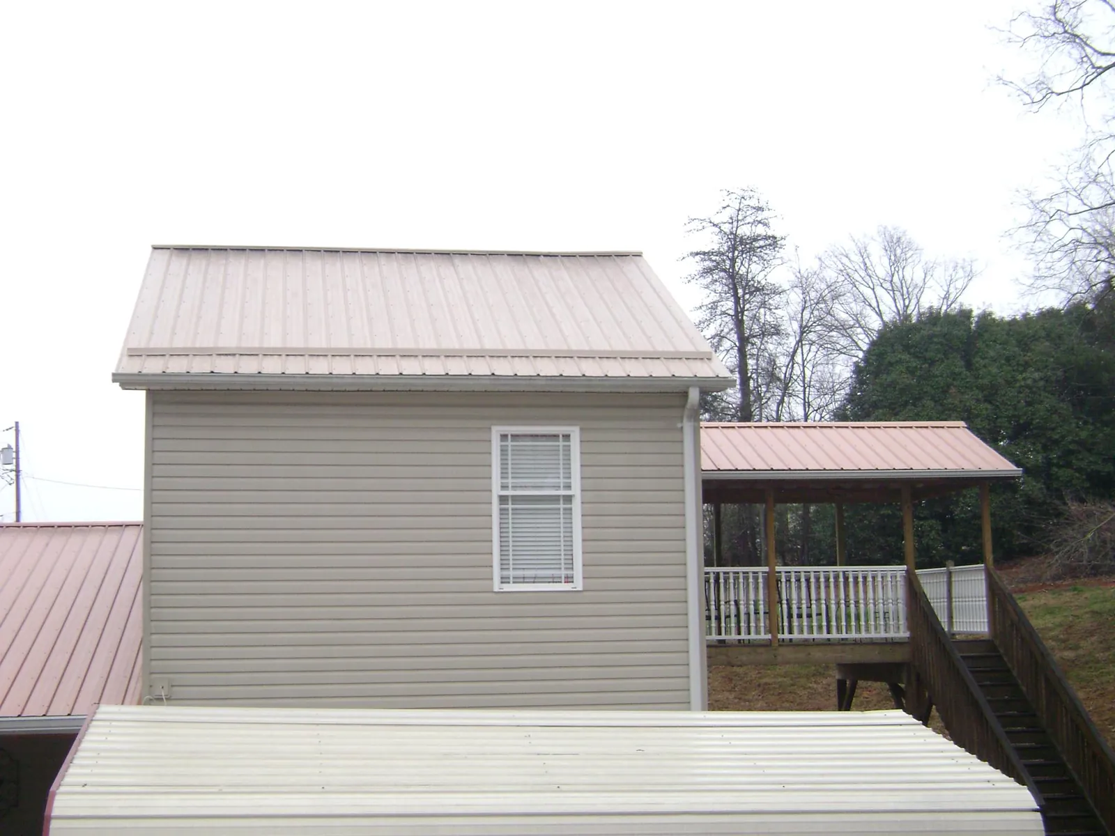 Tan metal roofs on a two story addition and attached porch, from a Roof Replacement job in Cammal