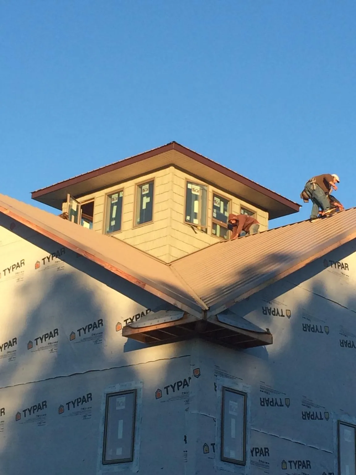 Roofers working around a rooftop cupola on a new metal roof at sunset — Roof Waterproofing in Cammal by Roofing Brothers